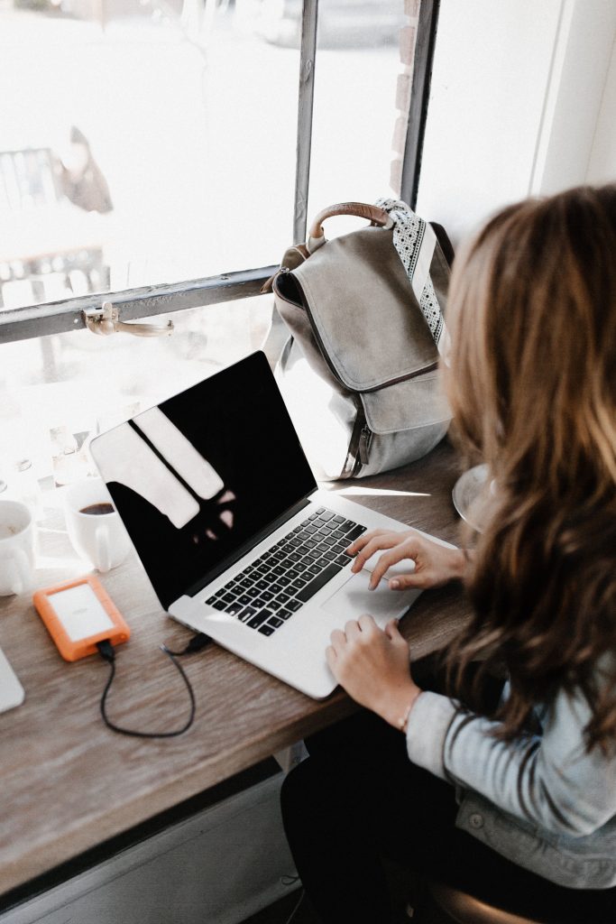 woman sitting by window looking at a laptop