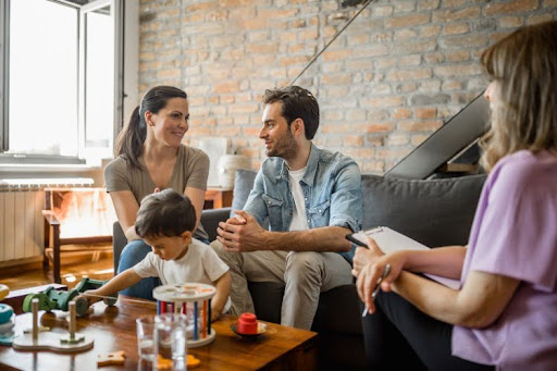 A therapist talks to a family in a home setting.