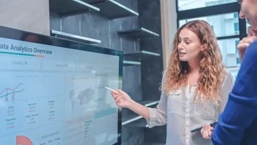A data analytics professional explaining a chart on a screen.
