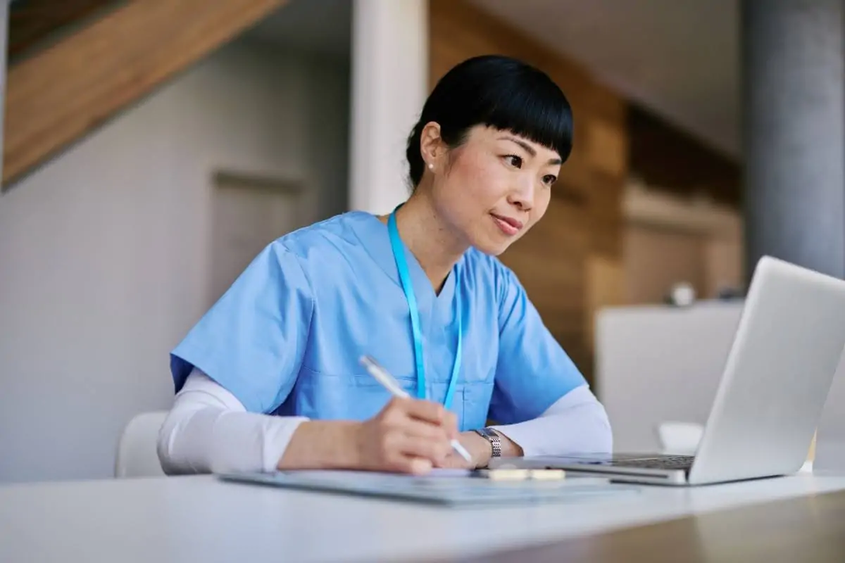 An RN takes notes during an online class in an RN to BSN degree program.