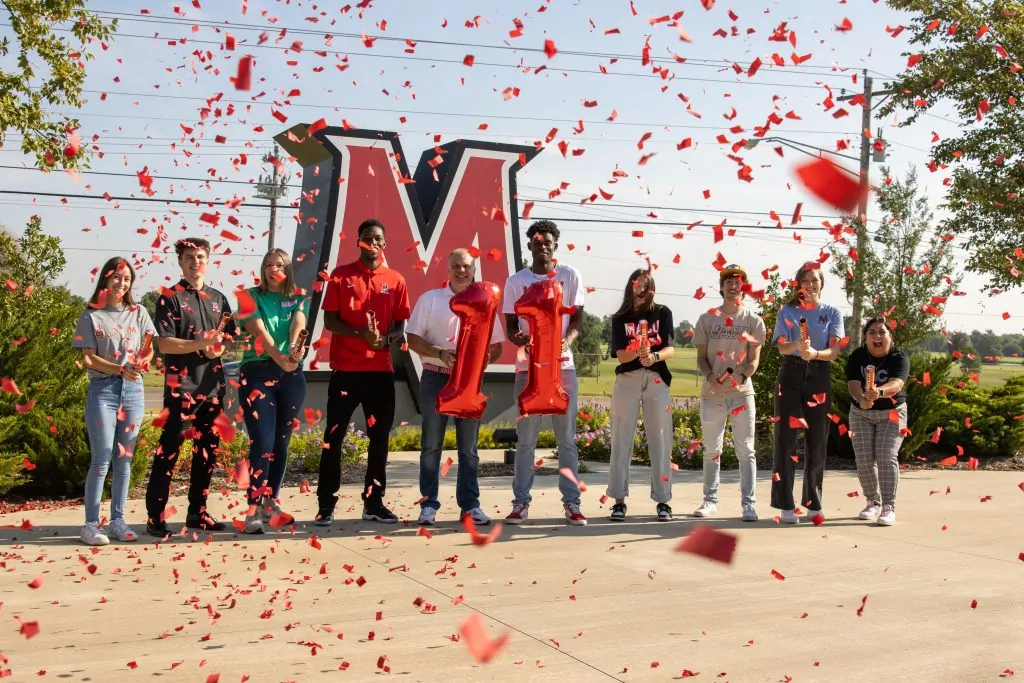 President Greenwald and students celebrate with confetti and balloons.